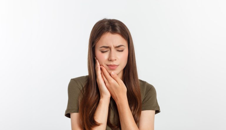 Teen woman pressing her bruised cheek with a painful expression as if she is having a terrible tooth ache